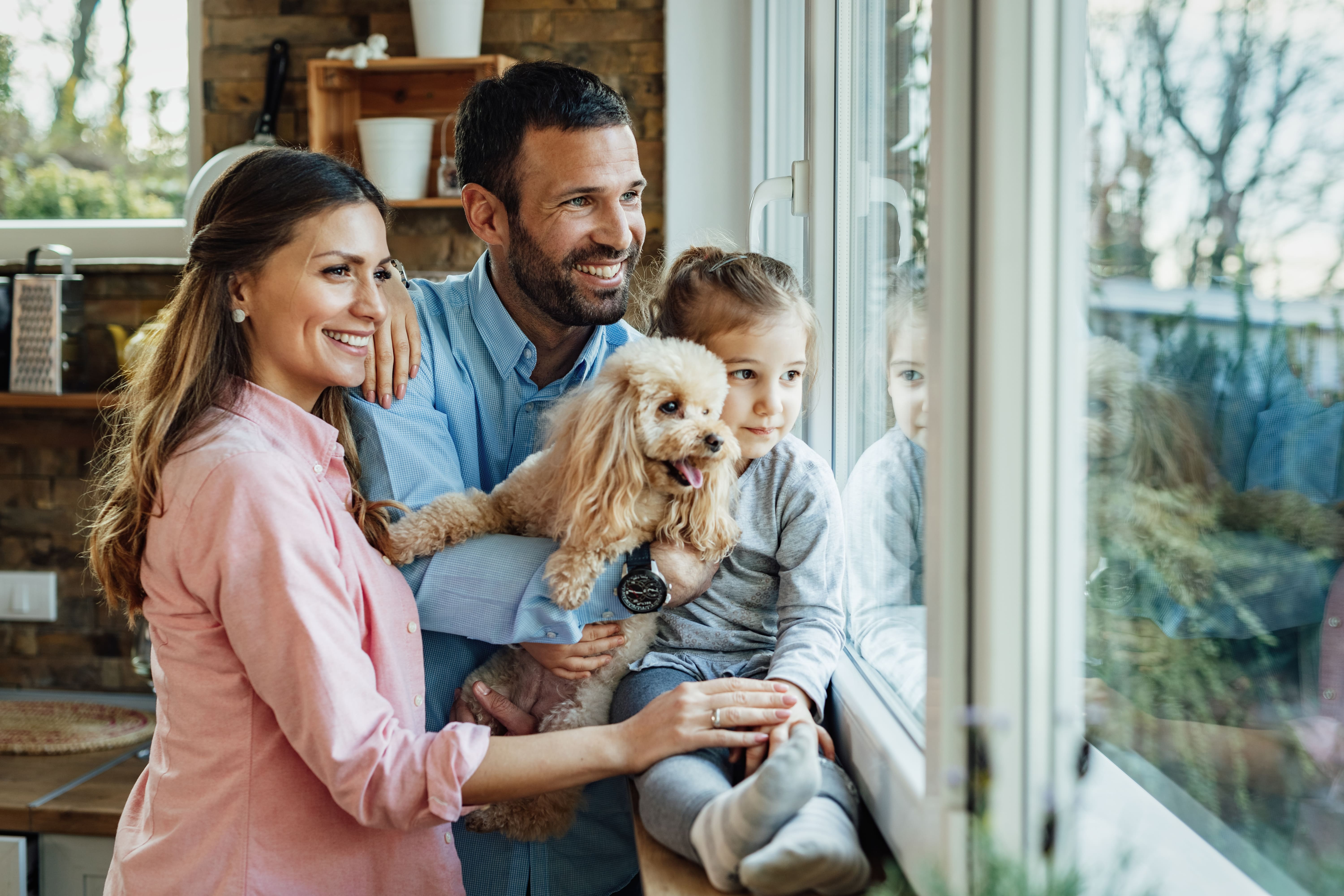 Família sorridente em casa, junto à janela